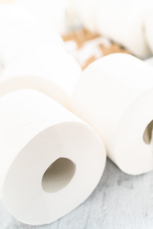 New and empty white toilet paper rolls on a gray background.
