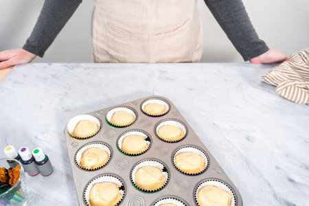 Vanilla cupcake batter in foil cupcake liners to bake Mardi Gras vanilla cupcakes.