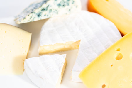 Variety of large wedges gourmet cheese on a white background.