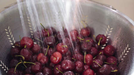 Washing red cherries in stainless steel colander.の写真素材
