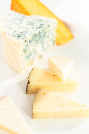 Variety of large wedges gourmet cheese on a white background.