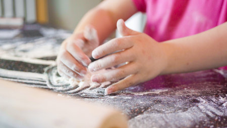 Little girl rolling out pizza dough for individual small pizzas.の写真素材