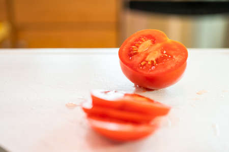 Slicing red tomato on a white cutting board.の写真素材
