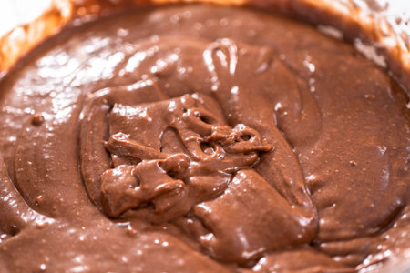 Chocolate cake batter in a mixing glass bowl ready for baking bundt cake.
