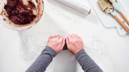 Step by step. Flat lay. Wrapping cookie dough into the plastic wrap to bake chocolate cookies.の写真素材