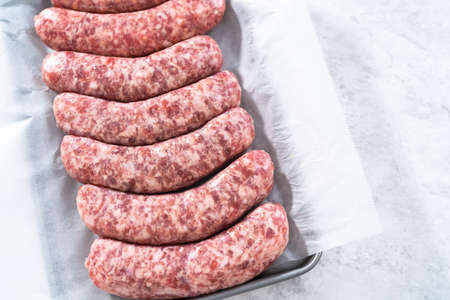 Raw beer bratwursts in the row on a small tray.の写真素材