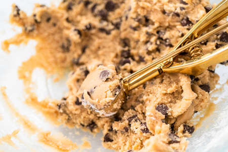 Homemade cookie dough with chocolate chips in a glass mixing bowl.の写真素材