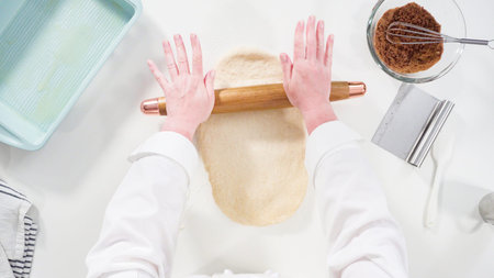 Flat lay. Rolling dough with a french rolling pin to bake cinnamon rolls.
