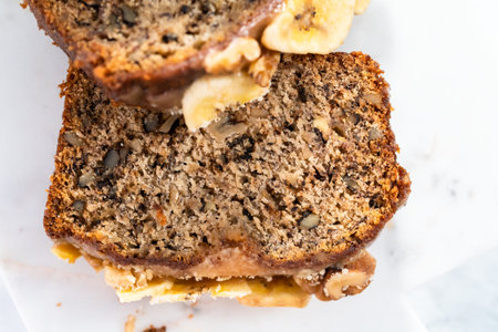 Sliced banana nut bread with drizzled with homemade caramel on a marble cutting board.