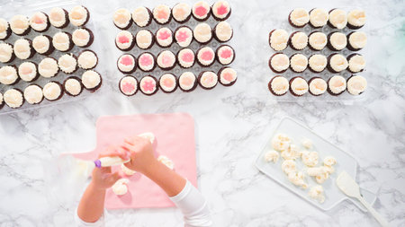 Flat lay. Step by step. Little girl practicing piping buttercream frosting into a cutting boardの写真素材