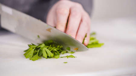 Curring vegetables on a white cutting board to cook vegetarian white bean soup.の写真素材