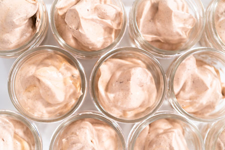 Scooping mixture into the small glass jars to make homemade chocolate ice cream.