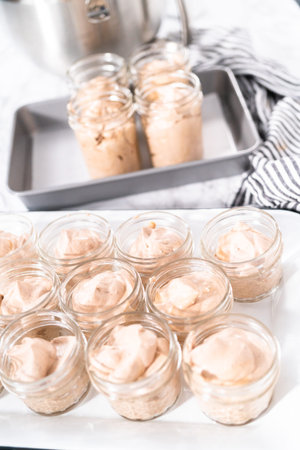 Scooping mixture into the small glass jars to make homemade chocolate ice cream.