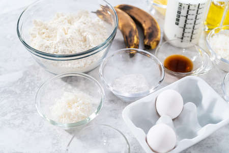 Measured ingredients in glass mixing bowls to prepare coconut banana pancakes for breakfast.の写真素材