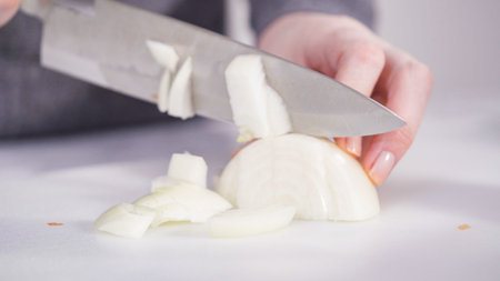 Curring vegetables on a white cutting board to cook vegetarian white bean soup.