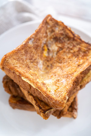 Stack of freshly baked french toast on a white plate.