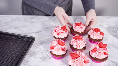 Step by step. Decorating red velvet cupcakes with chocolate red hearts and kisses.の写真素材