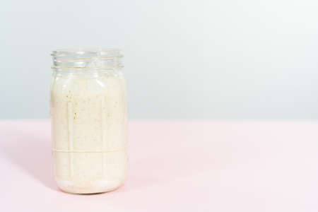 Feeding sourdough starter in a glass mason jar for baking artisan bread.の写真素材