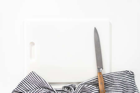 White cutting board with a knife on a white background.の写真素材
