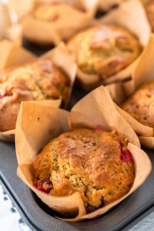 Freshly baked cranberry muffins in brown paper muffin cups.