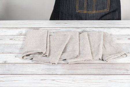 Folding a natural color linen dinner napkin on a white wooden table.の写真素材