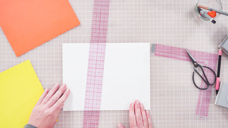 Flat lay. Little girl making a handmade Father's Day card from construction paper.