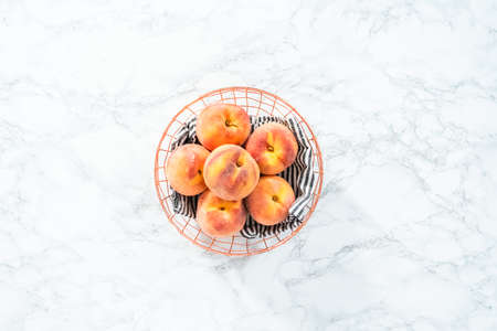 Organic whole peaches in a metal wired basket.の写真素材
