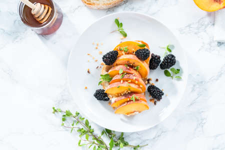 Peach ricotta toast garnished with blackberries on a white plate.の写真素材