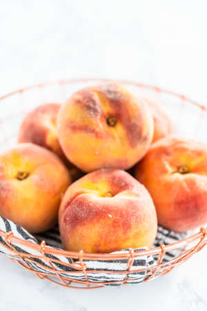 Organic whole peaches in a metal wired basket.の写真素材