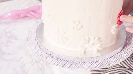 Step by step. Decorating round funfetti cake with pink and white fondant snowflakes.の写真素材