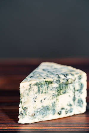 Large wedge of blue cheese on a dark wooden background.の写真素材