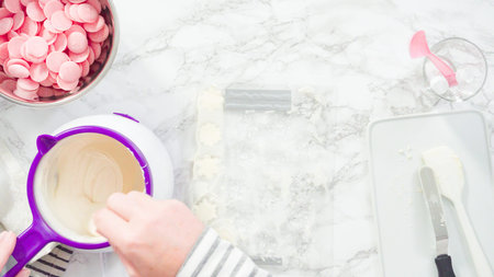 Flat lay. Step by step. Pouring melted chocolate into a plastic chocolate mold in the shape of...