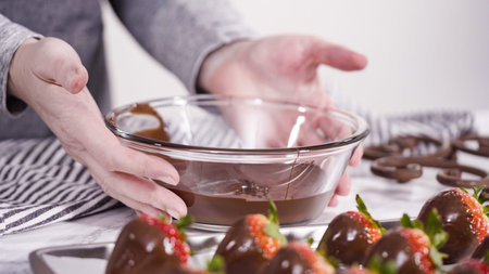 Step by step. Dipping organic strawberries into a bowl with melted chocolate to prepare chocolate covered strawberries.の写真素材