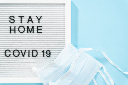 STAY HOME and COVID-19 sign on message board with a blue medical mask.の写真素材