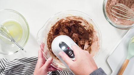 Step by step. Flat lay. Mixing ingredients in a glass mixing bowl to bake chocolate cookies.
