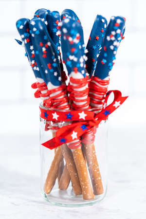 Homemade chocolate-covered pretzel rods decorated like the American flag in a glass jar.の写真素材