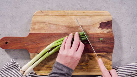 Cutting organic green onions on a wood cutting board.の写真素材