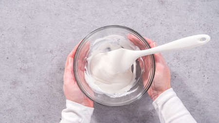 Flat lay. Step by step. Mixing ingredients in a glass mixing bowl to prepare the white glaze.の写真素材