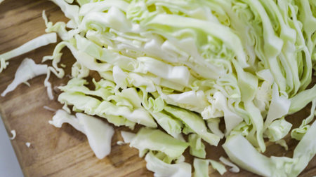 Step by step. Shredded organic cabbage on a wood cutting board.の写真素材