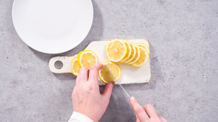 Flat lay. Step by step. Slicing organic lemon wedges on a white plate.の写真素材