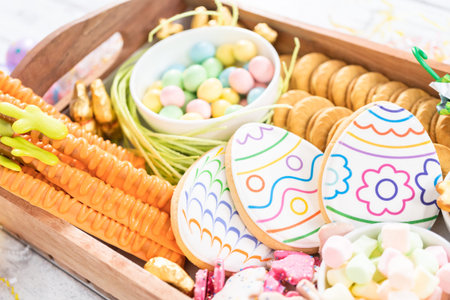 Assembling charcuterie board with Easter candies, cookies, and marshmallows.