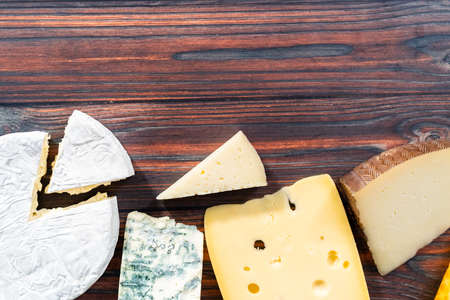 Variety of large gourmet cheese wedges on a dark wooden background.の写真素材