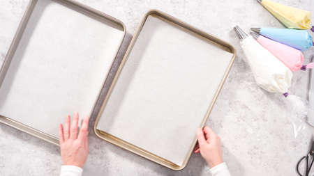 Flat lay. Step by step. Piping meringue mix into unicorn-shaped pops on a baking sheet lined with parchment paper.の写真素材