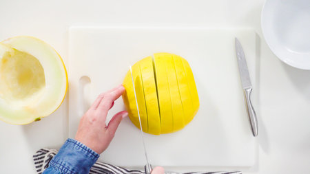Step by step. Flat lay. Slicong golden dewlicious melon on a white cutting board.