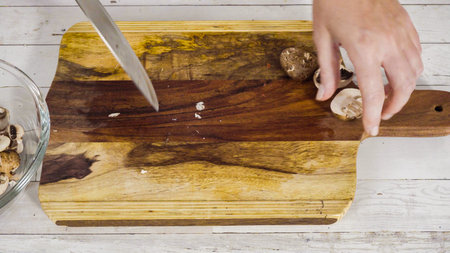 Cutting organic Bella mushrooms on a wood cutting board.の写真素材