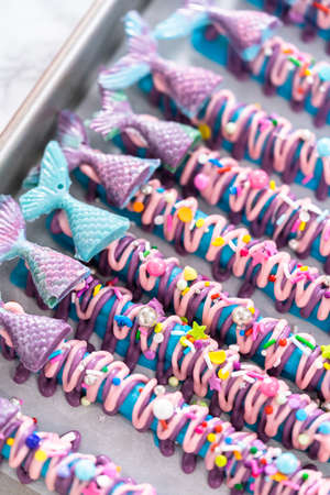 Mermaid chocolate pretzel rods drizzled with pink and purple chocolate and covered with sprinkles.の写真素材
