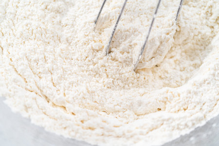 Mixing ingredients in a glass mixing bowl to prepare coconut banana pancakes.の写真素材