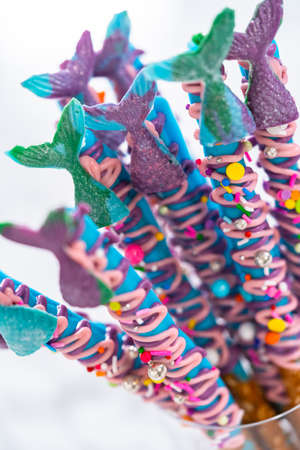 Mermaid chocolate pretzel rods drizzled with pink and purple chocolate and covered with sprinkles.の写真素材