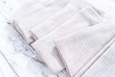Closeup view of a natural color linen dinner napkin on a wooden white table.の写真素材