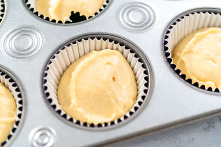 Vanilla cupcake batter in foil cupcake liners to bake Mardi Gras vanilla cupcakes.の写真素材